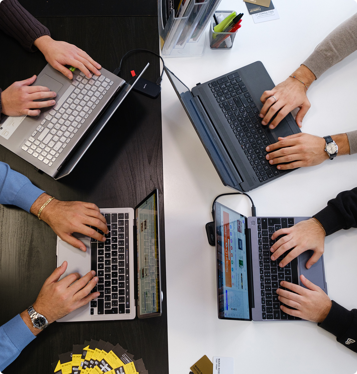 Foto ufficio con 4 persone Una foto dall'alto su una scrivania dove ci sono 4 computer portatili con 4 persone che lavorano al PC